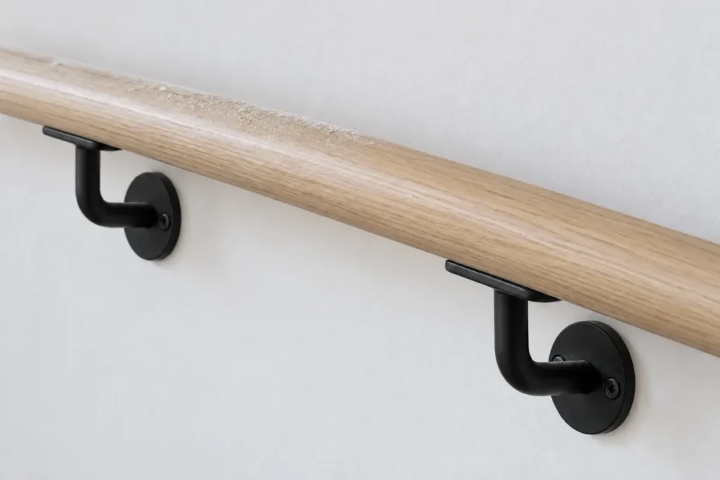 Oak handrail on black wall brackets with plaster dust along its top – builders cleaning in Preston