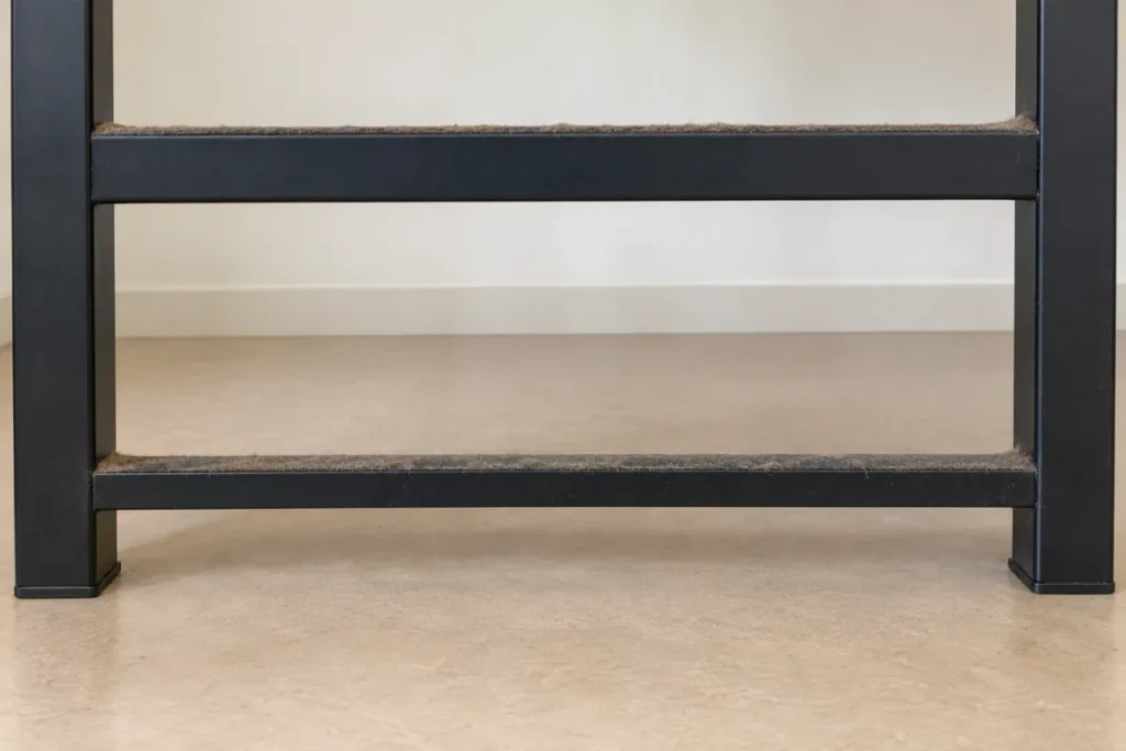 Black metal desk frame with dust built up along both crossbars – commercial cleaning in Bentleigh