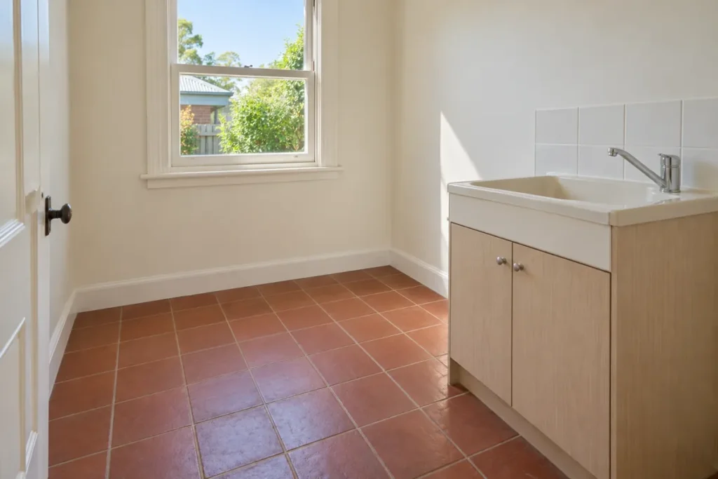 Clean laundry with terracotta floor tiles and a timber trough cabinet – deep cleaning in Tuggeranong