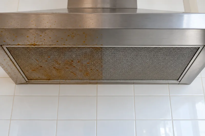 Stainless rangehood canopy and filter with grease spots, the right half cleaned – end of lease cleaning in Canberra