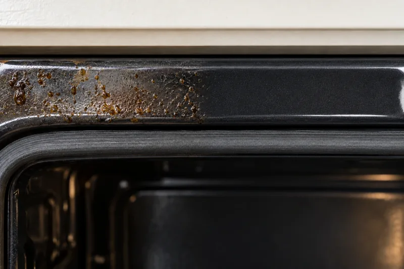 Oven front frame with grease spots on the left, the right half wiped clean – end of lease cleaning in Canberra