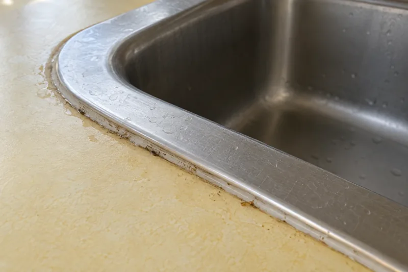 Grime and food residue along the rim where a steel sink meets the bench – end of lease cleaning in Geelong West