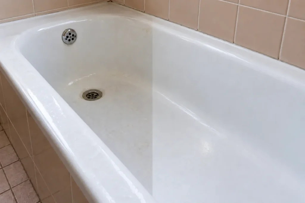 White bathtub with dull soap residue on the left, the right half glossy clean – end of lease cleaning in Jolimont