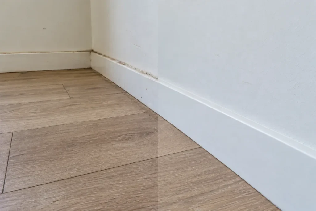 Grimy white skirting board above timber floor, the right half cleaned – end of lease cleaning in Melbourne