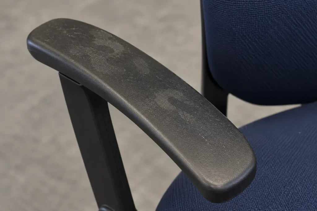 Black chair armrest dulled by palm smudges above a navy fabric seat – office cleaning in Belmont