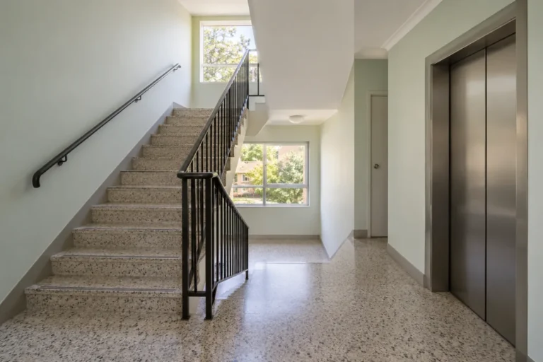 Terrazzo stairwell with black railings, landing window and a lift – strata cleaning in Melbourne