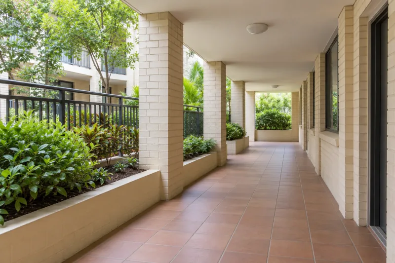 Covered walkway with brick columns and garden beds beside a courtyard – strata cleaning in North Canberra